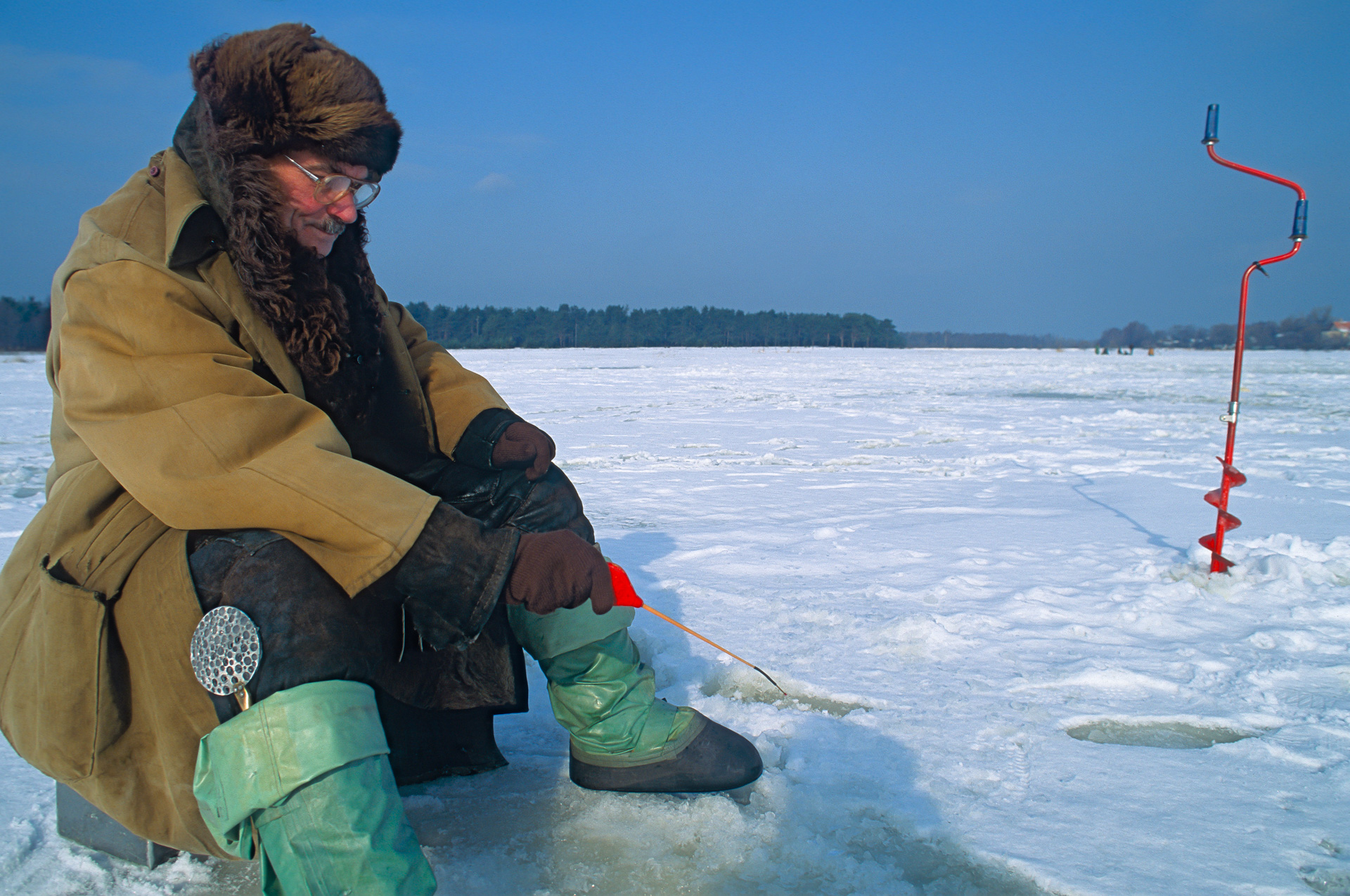 Winter im Baltikum in Lettland an der Ostsee bei Vecaki sitzen Eisangler am zugefrorenen Vecdaugava See
